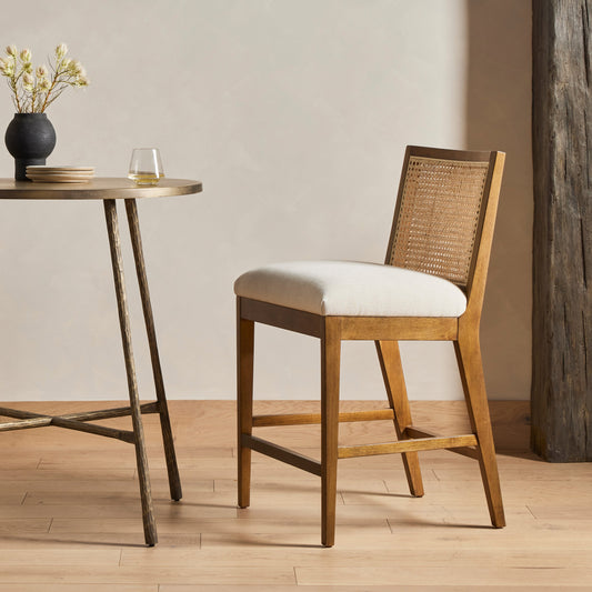 Antonia Cane Armless Bar Stool by Four Hands in savile flax, toasted parawood, brass kickplate. Made from 92% polyester, 8% flax, linen, solid parawood, iron in a coastal style.