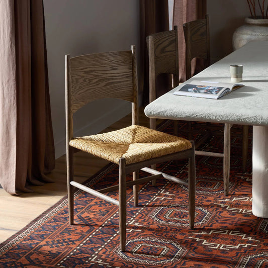 Jovan Dining Chair by Four Hands in stained saddle brown, slight dark bleaching. Made from solid oak, banana leaf in a traditional style.