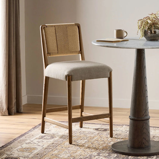 Rothler Bar Stool by Four Hands in alcala wheat, tan oak, double twisted paper cord. Made from 70% polyester, 20% viscose (rayon), 10% flax/linen, solid oak, rush in a transitional style.