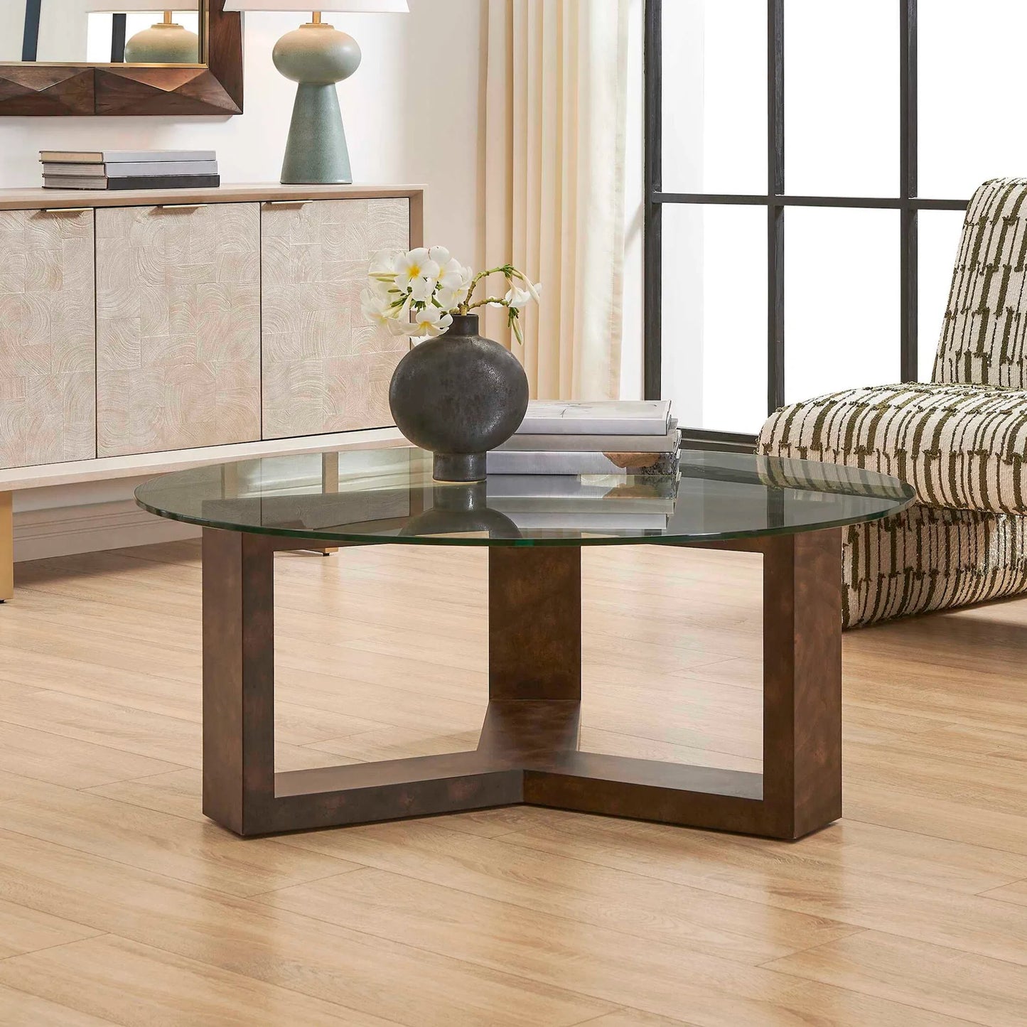 003 SI-2526286 | Lifestyle | Ignis Round Glass Coffee Table by Uttermost in brown, woodtone. Made from mappa burl veneered board, tempered glass 10mm, sheet metal plate in a unique style.
