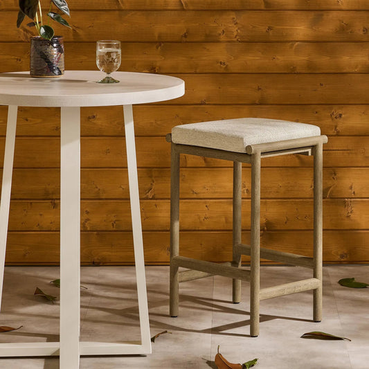 Kyla Outdoor Counter Stool by Four Hands in faye sand, washed brown. Made from 100% olefin, solid fsc®-certified teak, 91% polyurethane foam pad, 9% polyester fiber batting in a transitional style.