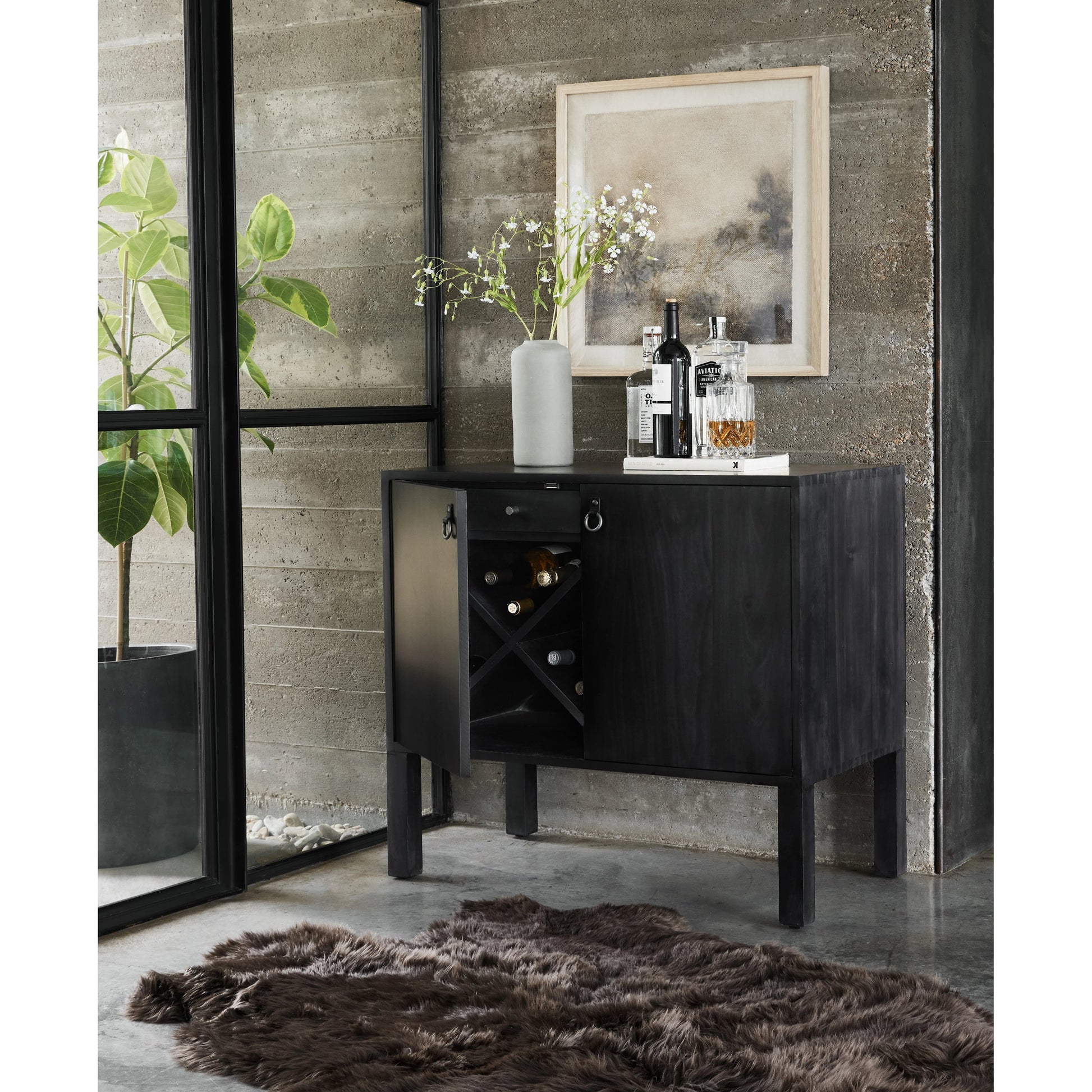 Isador Bar Cabinet by Four Hands in black wash poplar, natural iron, black leather and black wash poplar. Made from solid poplar, top grain leather in a modern style.
