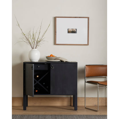 Isador Bar Cabinet by Four Hands in black wash poplar, natural iron, black leather and black wash poplar. Made from solid poplar, top grain leather in a modern style.
