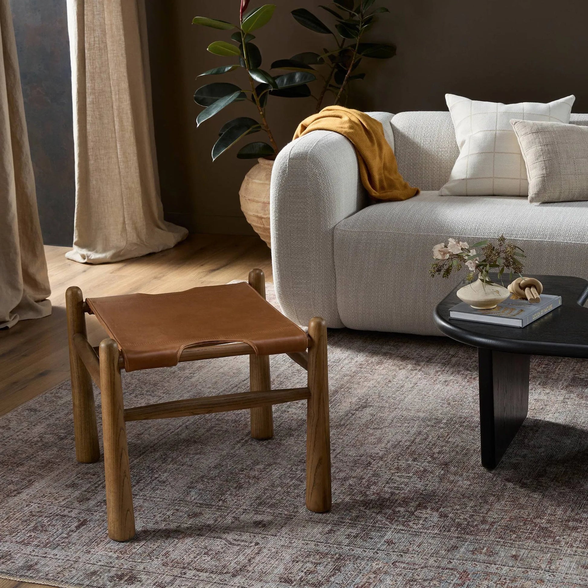 Nino Ottoman by Four Hands in dakota tobacco. Made from top grain leather, solid nettlewood, 100% polyester in a modern style.