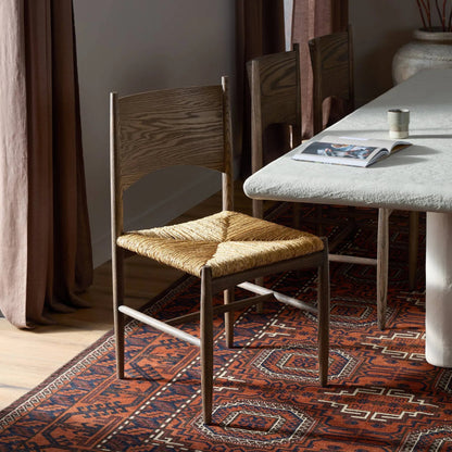 Jovan Dining Chair by Four Hands in stained saddle brown, slight dark bleaching. Made from solid oak, banana leaf in a traditional style.
