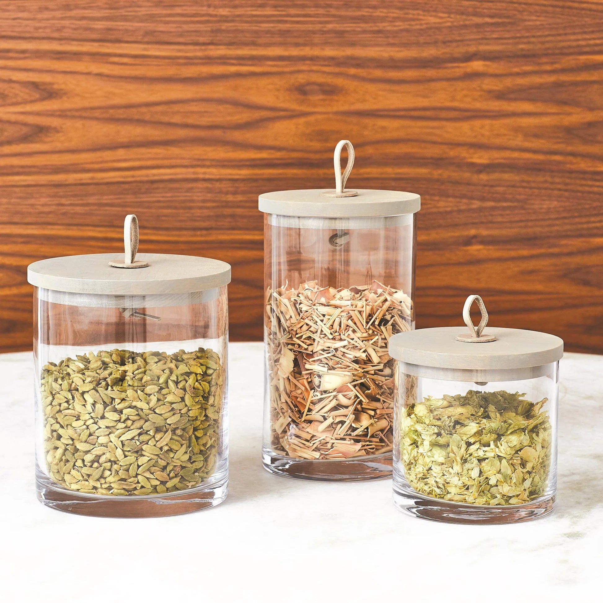 Rustic Canister by Global Views. Made from oak, glass, leather in a transitional style.