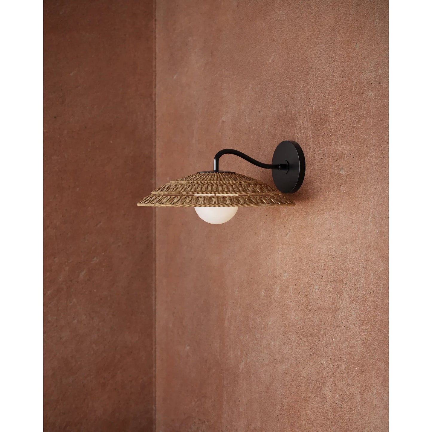 004 SI-2386955 | Lifestyle | Barbary Outdoor Wall Sconce by Currey and Company in natural, black, frosted white. Made from all-weather wicker, metal, glass in a rustic style.