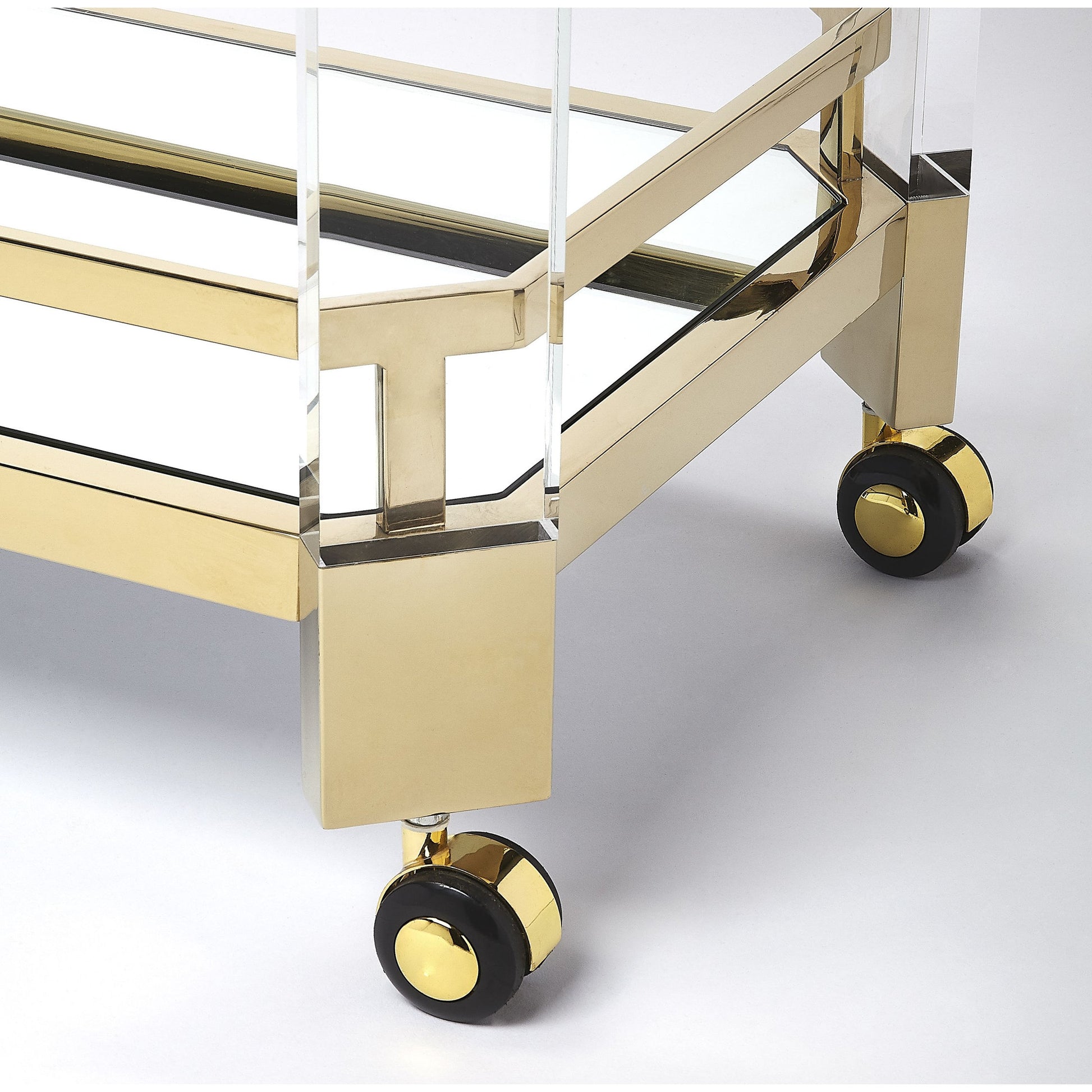 Charlevoix Serving Cart by Butler Specialty Company in gold and polished gold. Made from stainless steel, high polished gold, acrylic, clear glass, mirror glass, stainless steel casters, high polished gold finish in a transitional