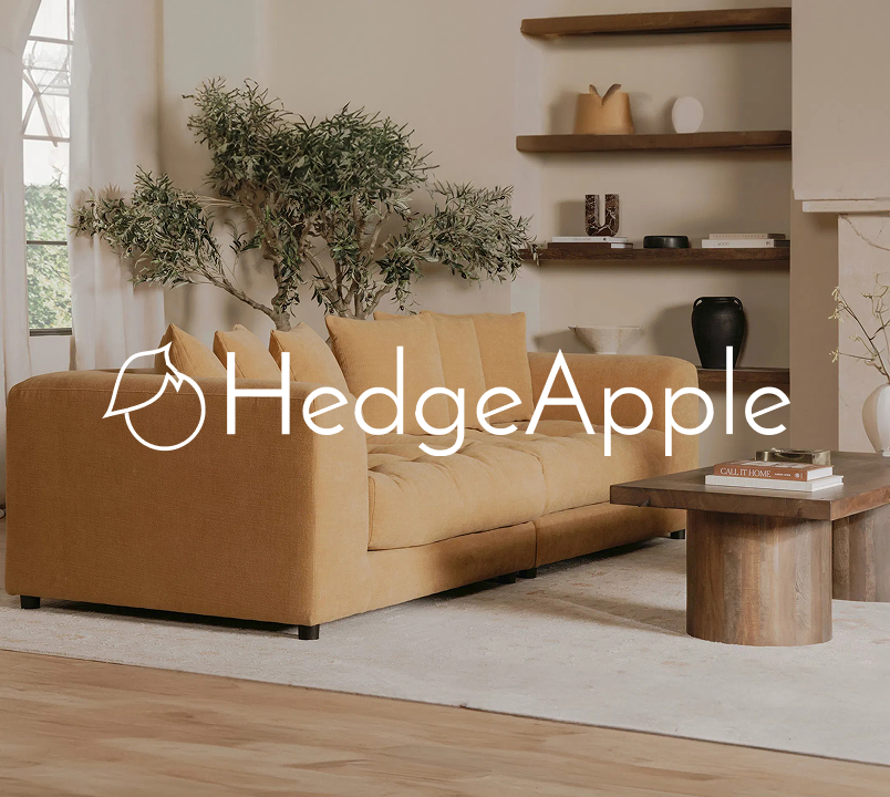 Modern living room with a mustard yellow sofa, wood coffee table, neutral rug, and styled shelves, featuring HedgeApple home décor branding.