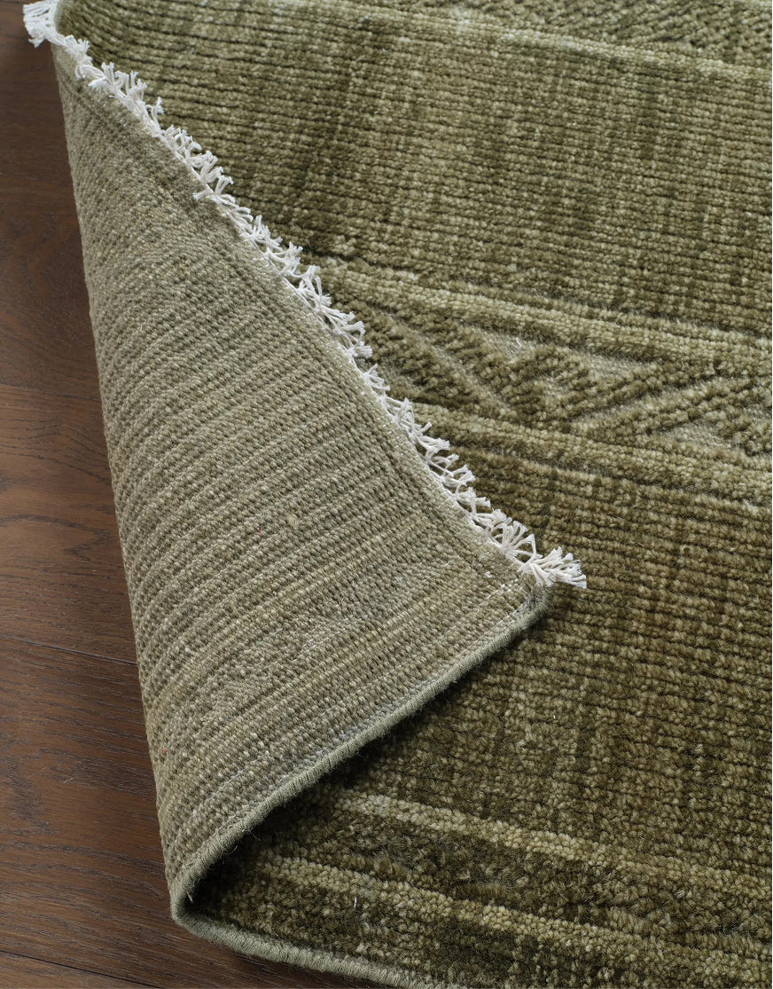 Green textured area rug with subtle pattern and fringe detail