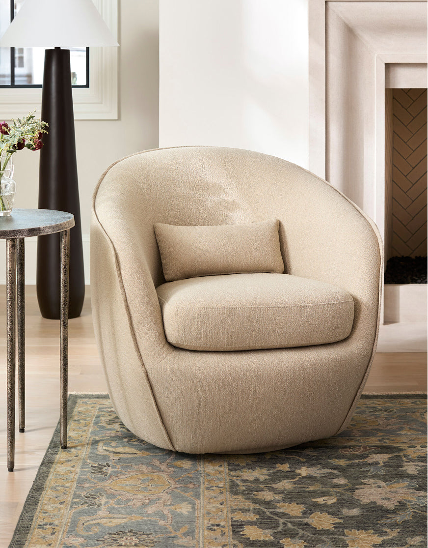 Curved beige accent chair with textured upholstery on patterned rug