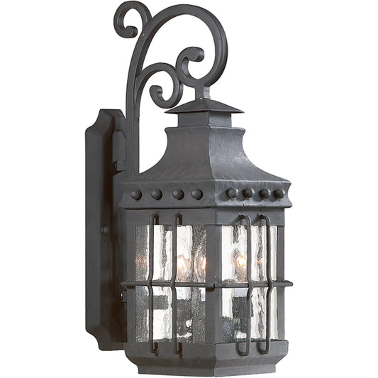 Dover Scroll Wall Lantern by Troy in natural bronze. Made from hand forged iron in a traditional style.