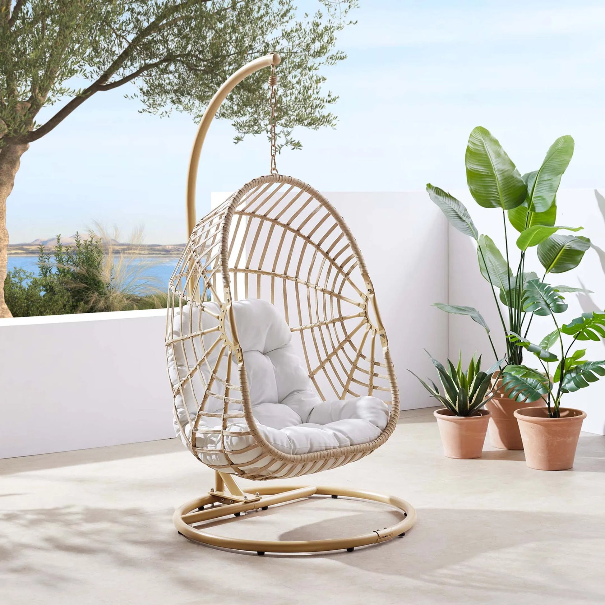 Gilmer Rattan Swing Chair by Evans & Londeen in natural white. Made from steel, rattan, rope, weimas white fabric, natural rattan #7x-302, stand, base in natural color mc03, spring holder, 2m chains (extra), 280mm chains in a cottage &
