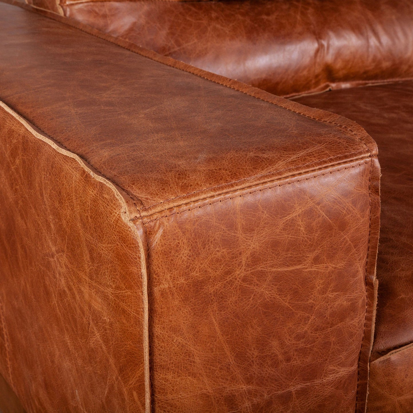 005 SI-2065543 | Closeup | Chiavari Modern Cognac Leather Sofa by World Interiors in cognac, antique zinc, oak. Made from leather, foam, oak wood & iron in a transitional style.