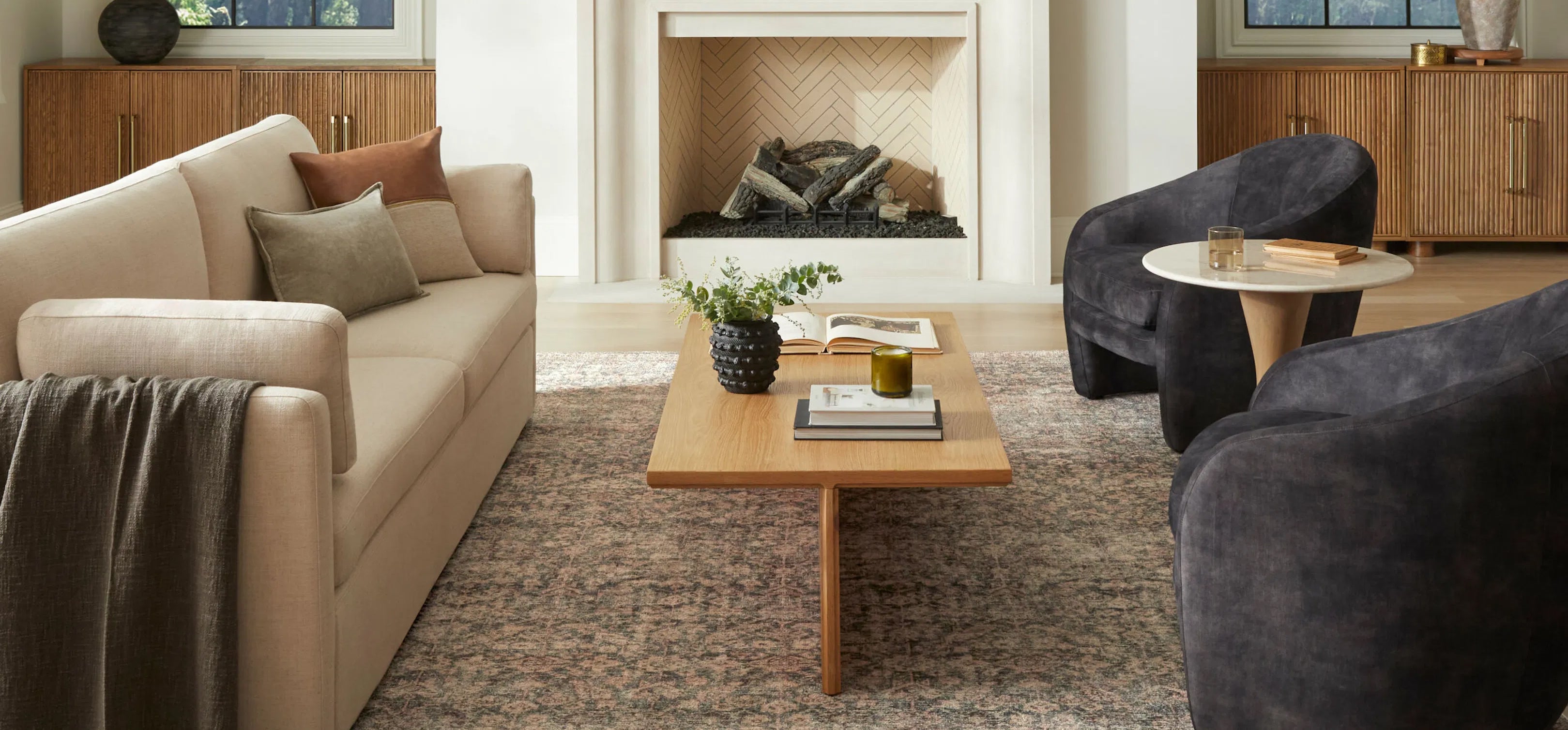 Modern living room with neutral sofa, wood coffee table, and sculptural chairs