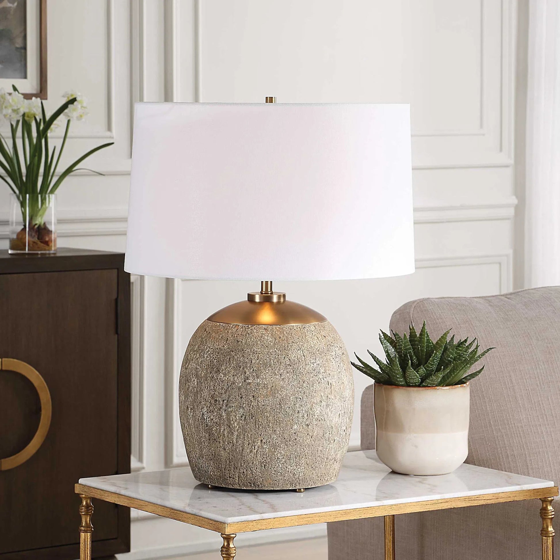 Raylan Textured Table Lamp by Uttermost in brass. Made from metal, cement, fabric in a modern style.