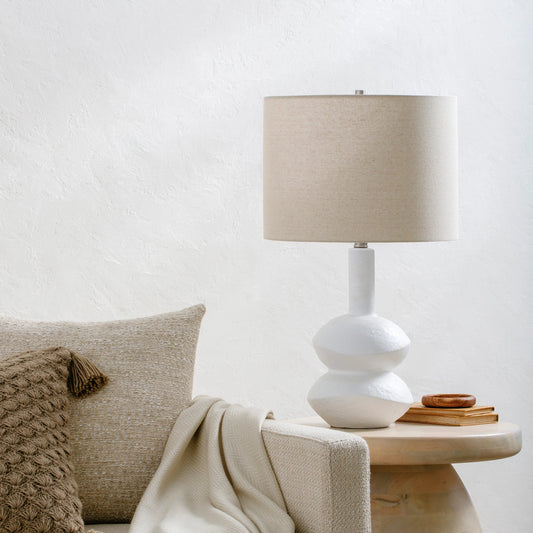 Mauna - 500115 by Surya in body: white, shade: wheat, finial: metallic - brass, harp: metallic - brass, cord: translucent and colored, polished. Made from body: ceramic, shade (outside): linen, shade (inside): polyester, finial