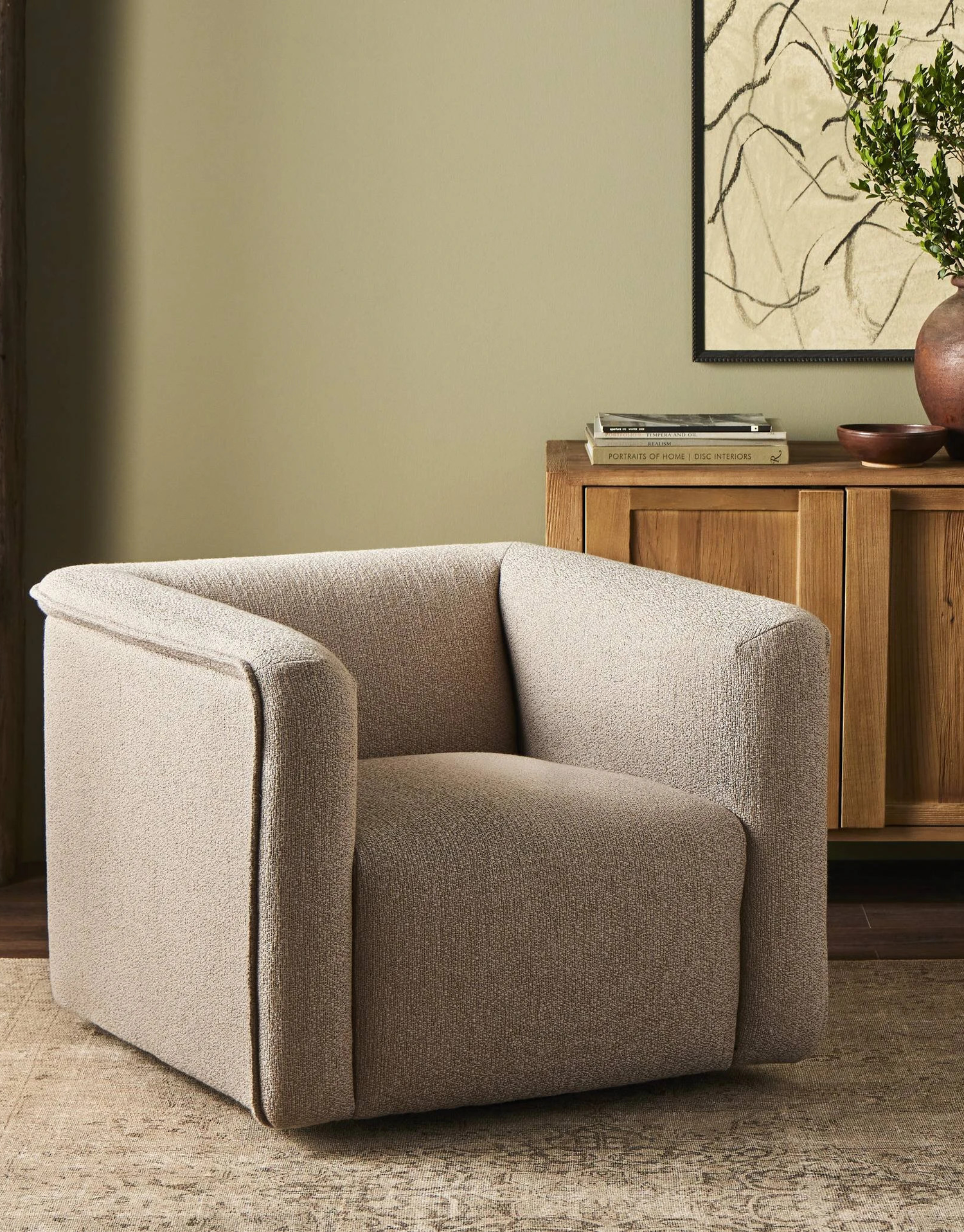 Modern beige accent chair with a sleek, boxy design, set in a cozy living room with a wooden sideboard and neutral decor accents.