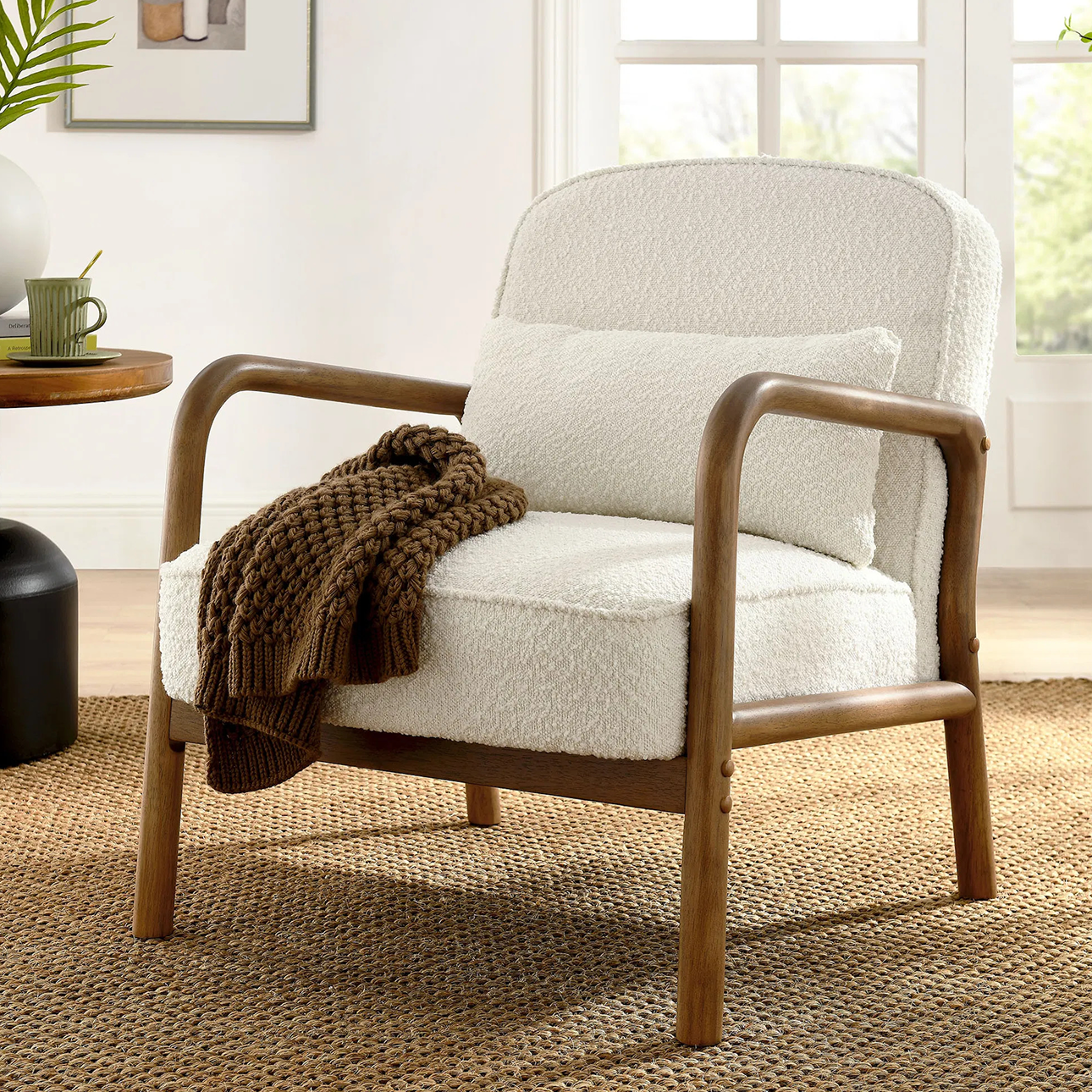 Modern accent chair with a curved wood frame and ivory boucle upholstery, styled with a knit throw in a cozy, sunlit living space—perfect for contemporary home decor.