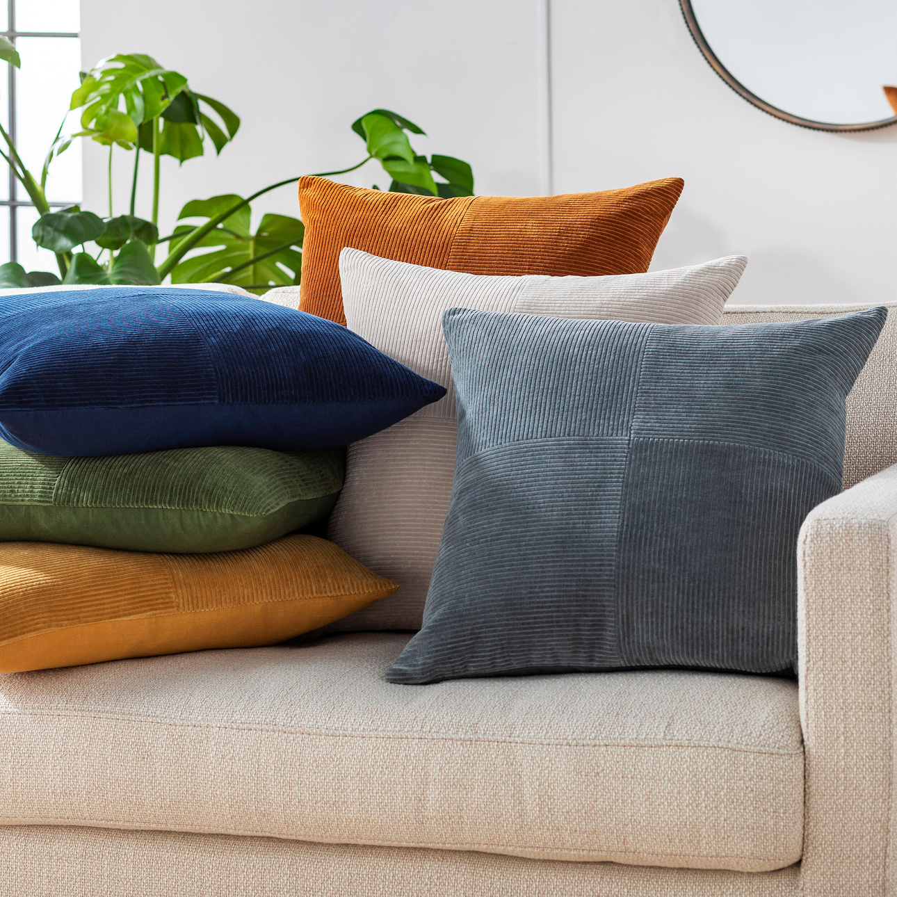 Colorful corduroy throw pillows in rich tones of blue, green, mustard, and rust styled on a modern cream sofa—shop decorative pillows now on sale.