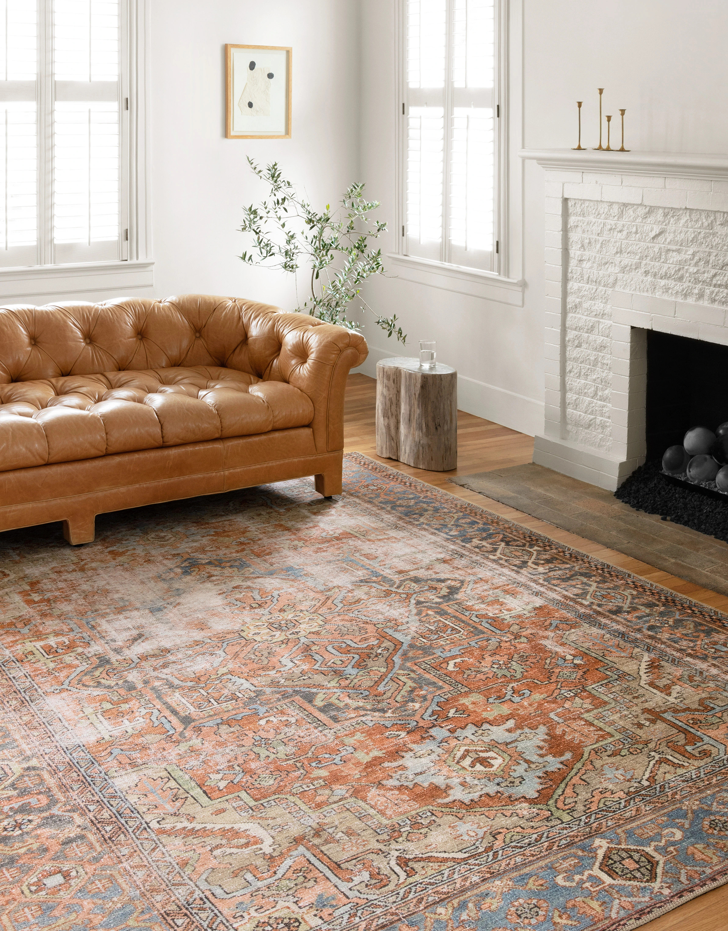 Stylish living room featuring a vintage-inspired area rug with a warm, intricate pattern, paired with a tufted leather sofa, and natural wood accents.